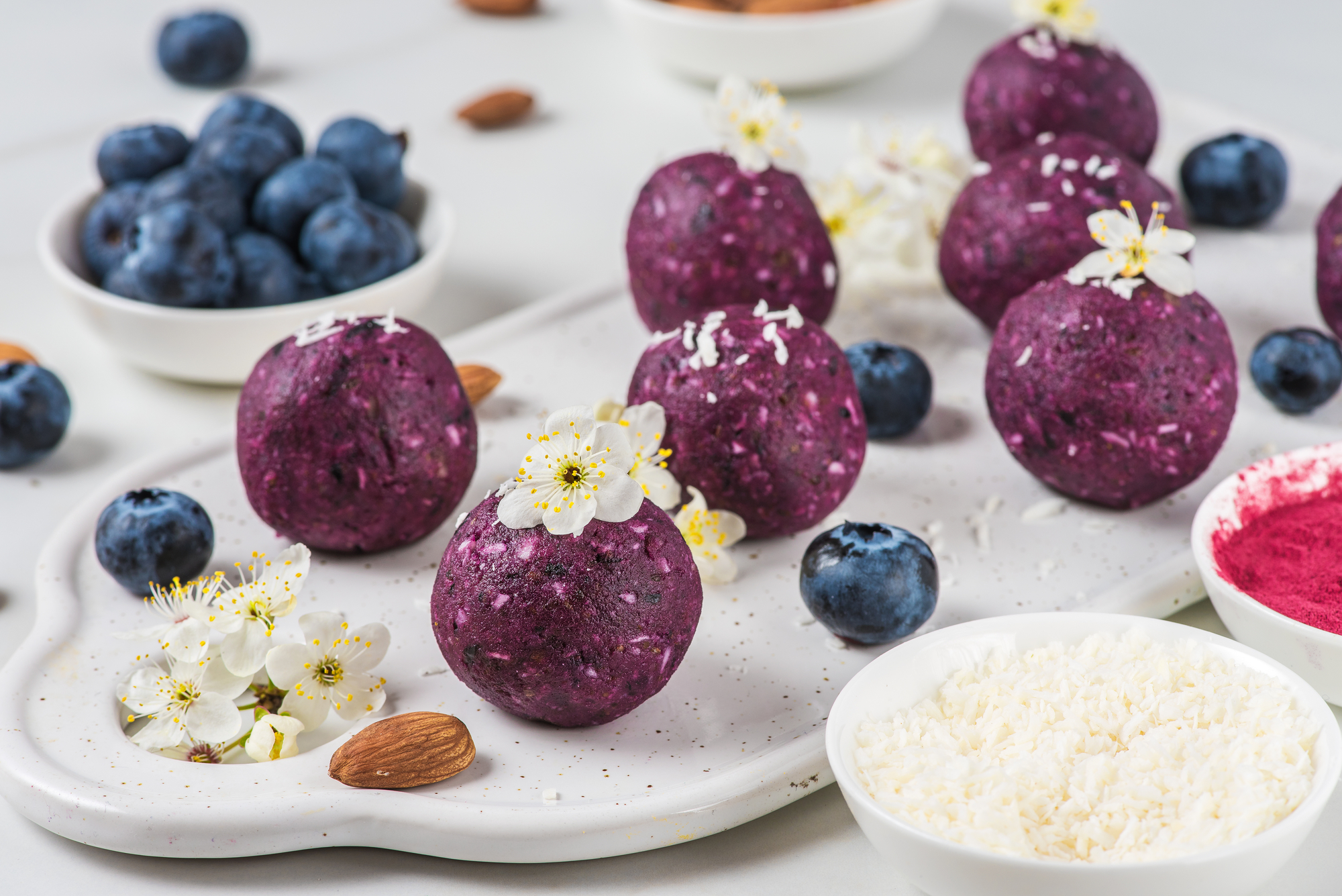 Raw vegan energy bites or balls made of blueberry and dates served with flowers.