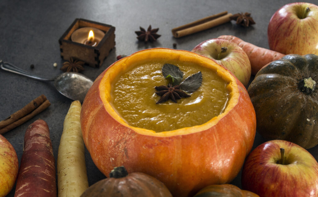 Butternut squash soup topped with star anise in a pumpkin bowl. 