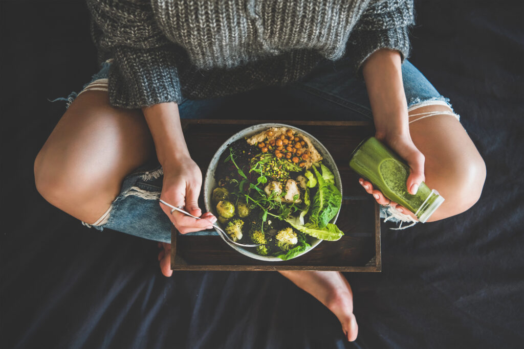 Woman eating plant-based salad and green smoothie. 