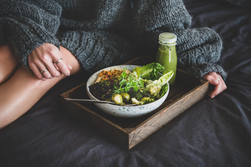 Woman eating a plant-based salad and green smoothie. 