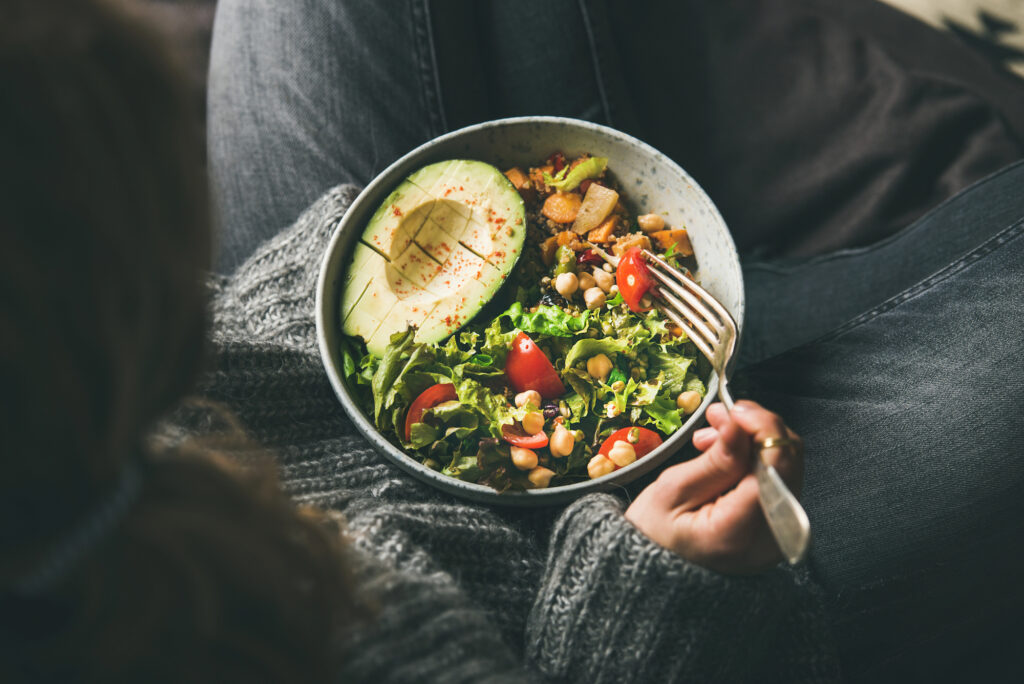 Woman eating a plant-based salad with avocado. 