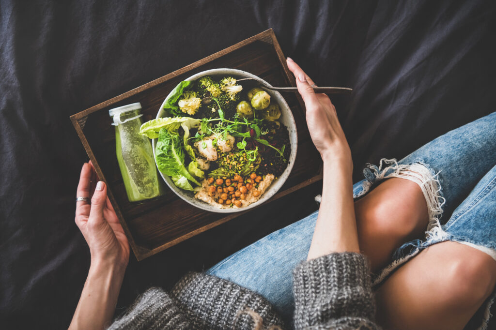 Woman eating a healthy plant-based salad and smoothie. 